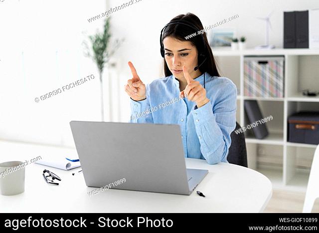 Customer service representative gesturing while talking on conference call on laptop at office