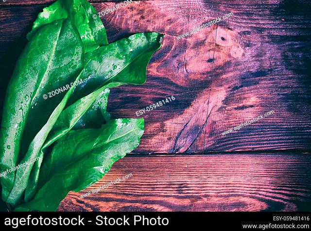 bunch of green sorrel on a brown wooden background, an empty space