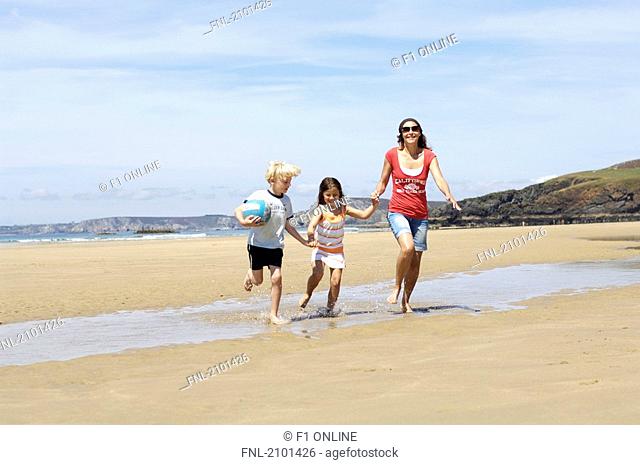 Woman running with her children on beach