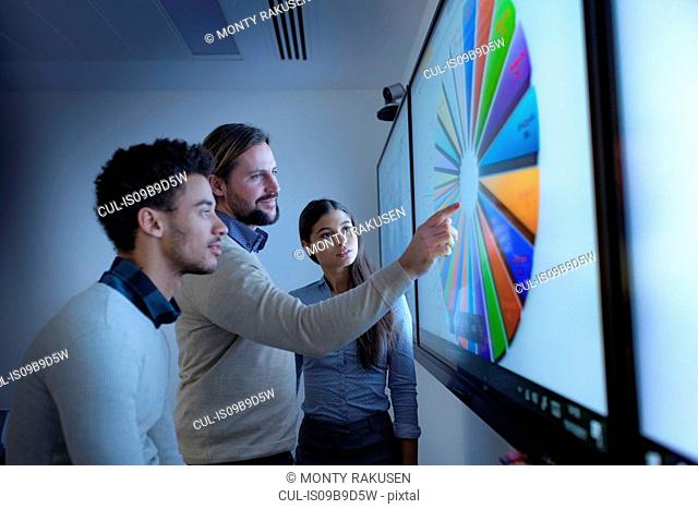 Teacher and apprentices studying graphical screen display in railway engineering facility