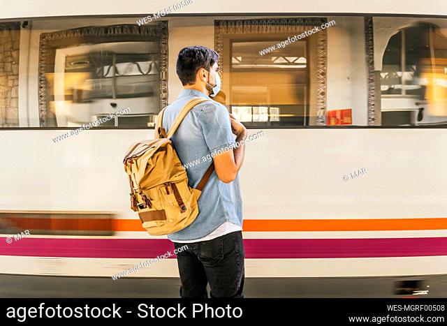 Man with backpack waiting for train at railroad station