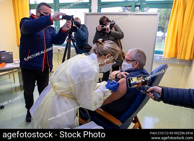 12 January 2021, Mecklenburg-Western Pomerania, Wismar: Nurse Ramona Radtke vaccinates paramedic Fred Knuth against Corona at the vaccination centre with the...