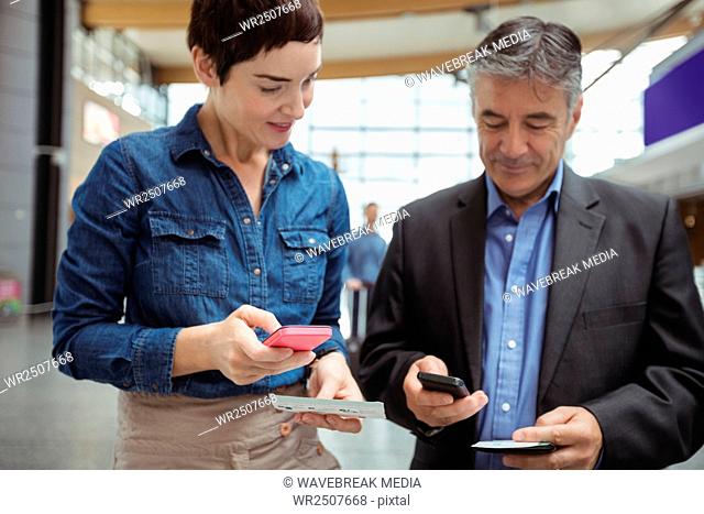 Business people holding boarding pass and using mobile phone