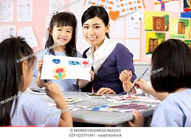 Teacher Helping Students During Art Class In Chinese School Classroom