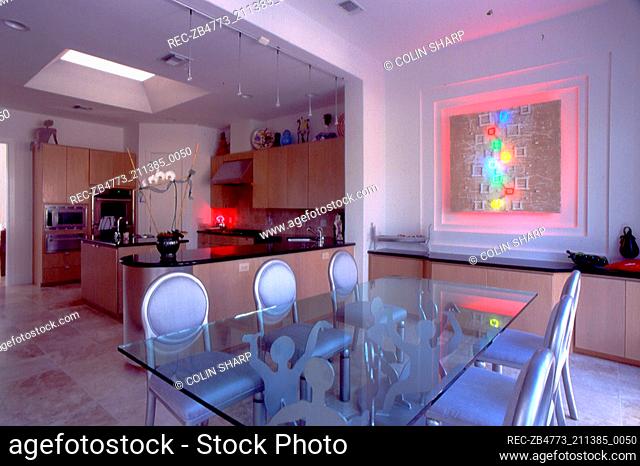 Glass dining table and upholstered chairs in open plan kitchen