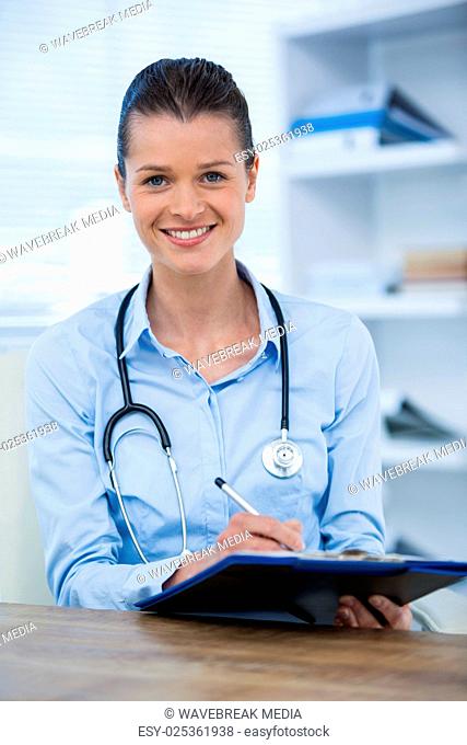 Portrait of female doctor writing on clipboard