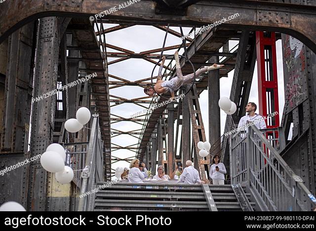 27 August 2023, Saxony-Anhalt, Magdeburg: Magdeburg artist Soleil entertains guests at a mass picnic (White Bridges Dinner) on the Hub Bridge