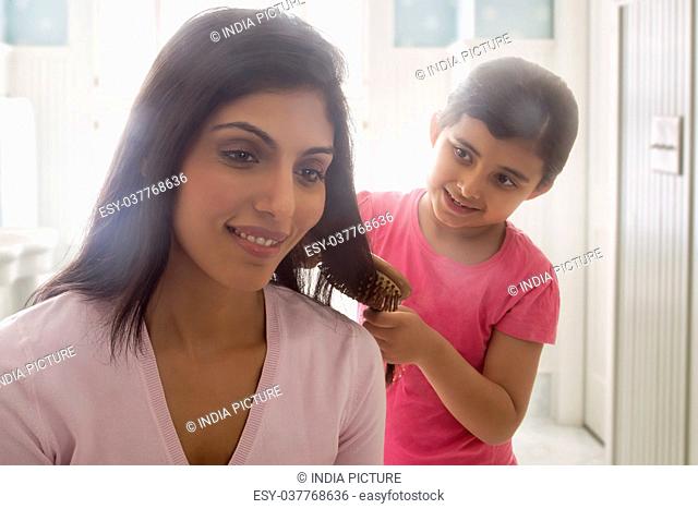 Close-up of girl combing mother's hair