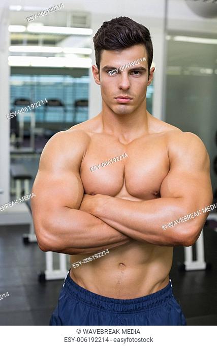 Serious young muscular man in gym