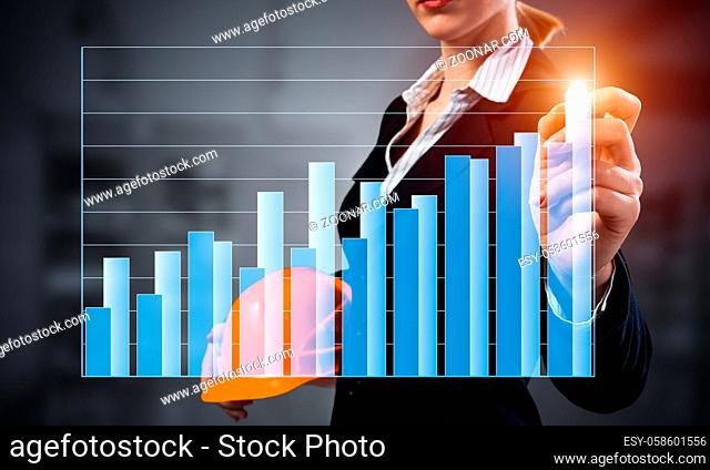 Businesswoman pointing on 3d financial chart. Woman in business suit standing with safety helmet. Digital technology and innovation in construction industry