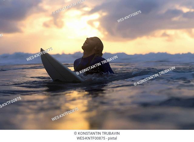 Indonesia, Bali, surfer in the ocean at sunrise