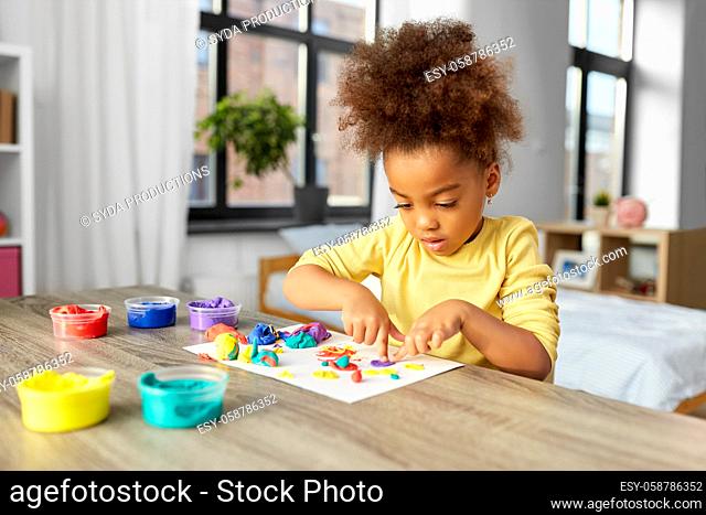little girl with modeling clay playing at home