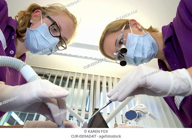 Dentist and dental nurse holding dental equipment