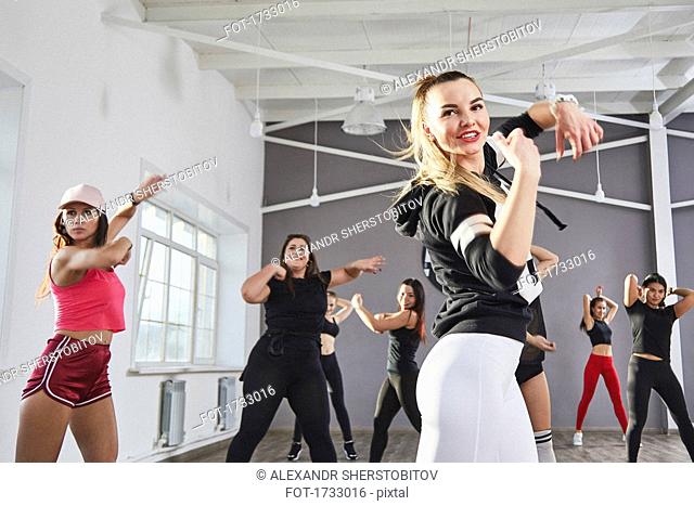 Smiling woman practicing dance with friends in studio