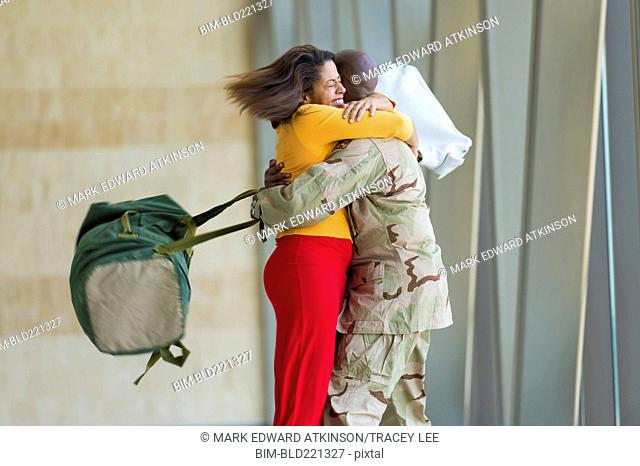 African American soldier hugging wife in airport