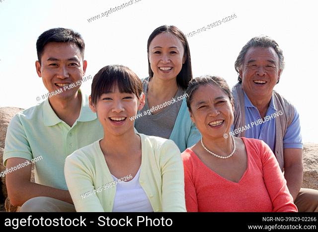 Portrait of smiling multigenerational family sitting on the rocks outdoors, China