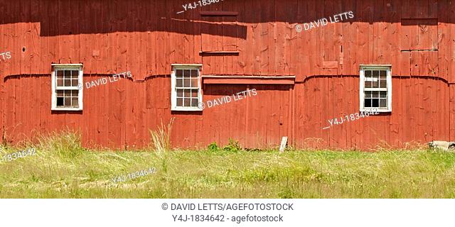 Three White Wood Windows on a Red Weathered Farm Barn of New Jersey