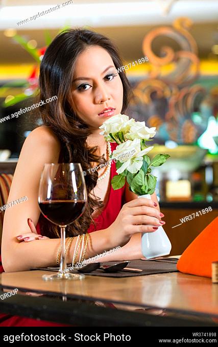Chinese nervous, hoping, lonely, dreamy, heartsick woman in a restaurant waiting for a date got stood up