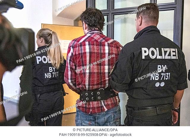 18 September 2019, Bavaria, Regensburg: The accused is led by police into the courtroom of the regional court. In the opinion of the public prosecutor's office