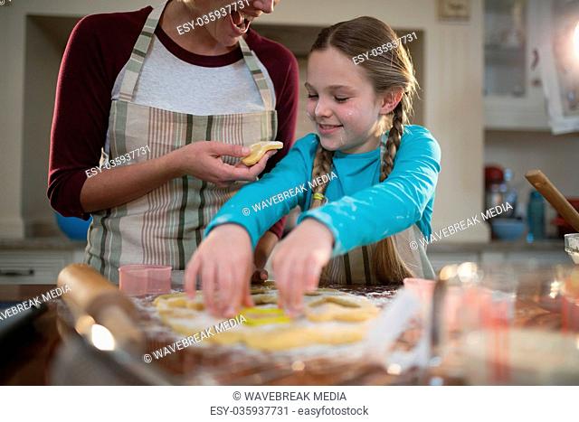 Mother and daughter preparing cookies in kitchen