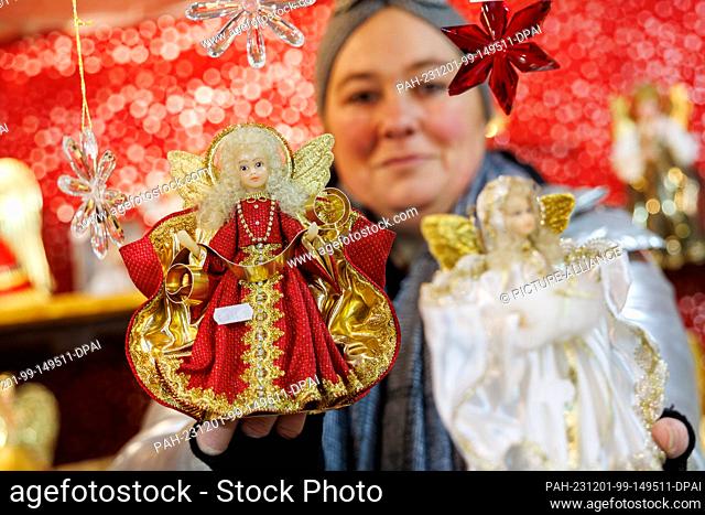 01 December 2023, Bavaria, Nuremberg: A stall vendor holds a tinsel angel in her hands at the Nuremberg Christmas Market