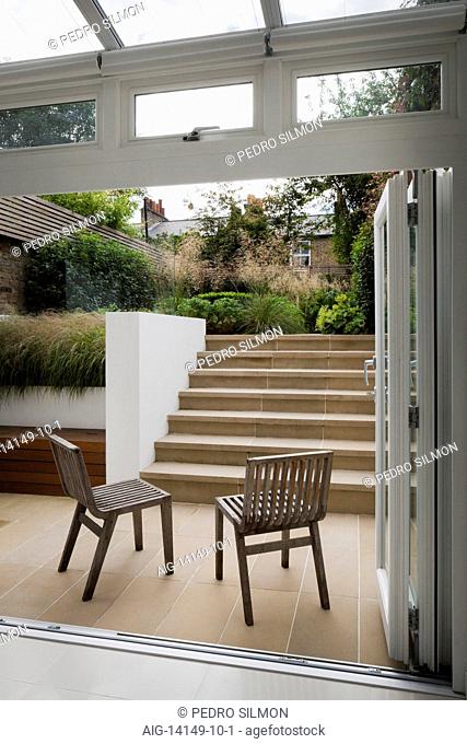French windows open onto the lower York stone paved outside area, with benchstore and York stone steps leading up to the larger, upper level