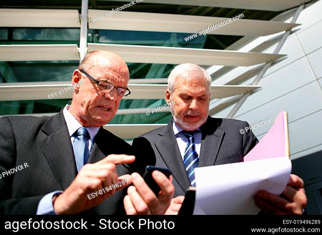 Portrait of older men in suits talking Documents