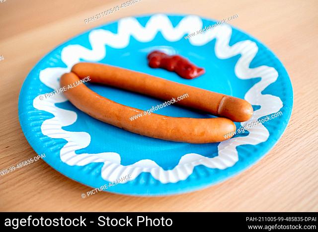 ILLUSTRATION - 01 October 2021, Lower Saxony, Oldenburg: A paper plate with two bockwursts and ketchup stands on a table