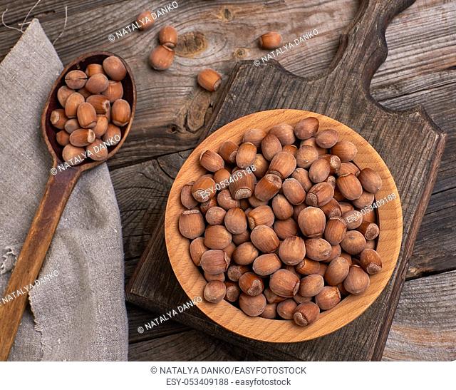 hazelnut nuts in a brown wooden bowl on a cutting board, close up