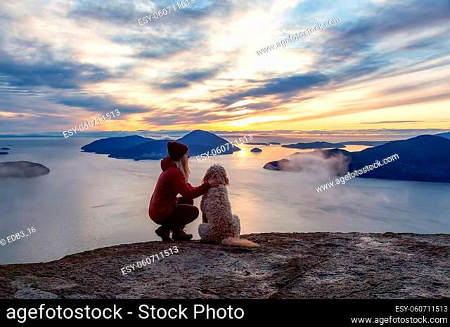 Adventurous Hiking on top of a Mountain with a dog during a colorful sunset. Taken on Tunnel Bluffs Hike, near Vancouver and Squamish, British Columbia, Canada