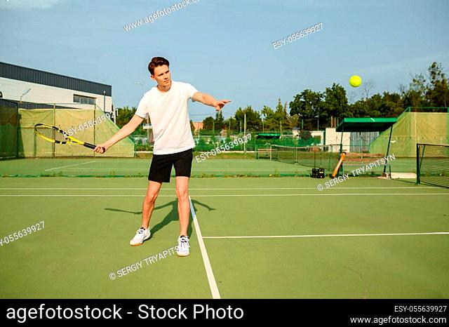 Male tennis player with racket hits the ball on outdoor court. Active healthy lifestyle, sport game competition, fitness training with racquet