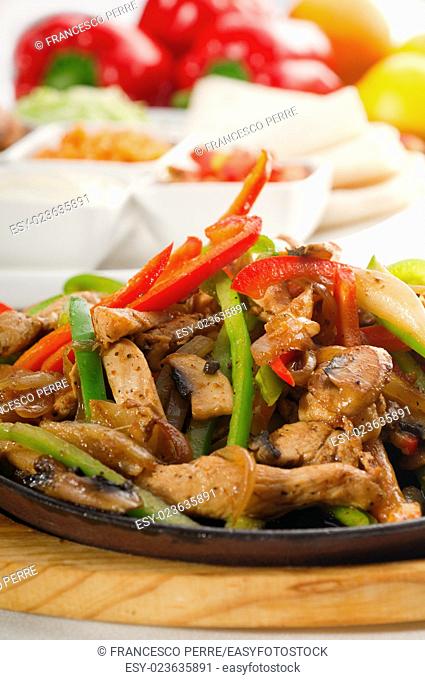 original fajita sizzling smoking hot served on iron plate and fresh vegetables on background
