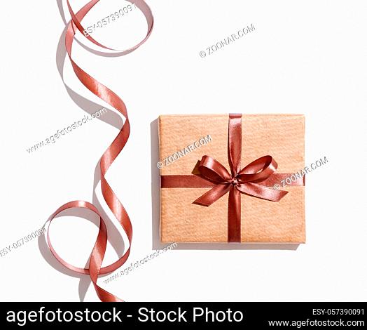 Craft gift box with curved brown ribbon isolated on white background