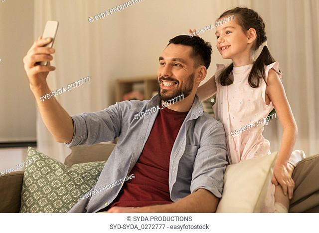 father and daughter taking selfie at home