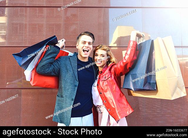 Beautiful young loving couple carrying shopping bags and enjoying together. Picture showing young couple shopping in the city