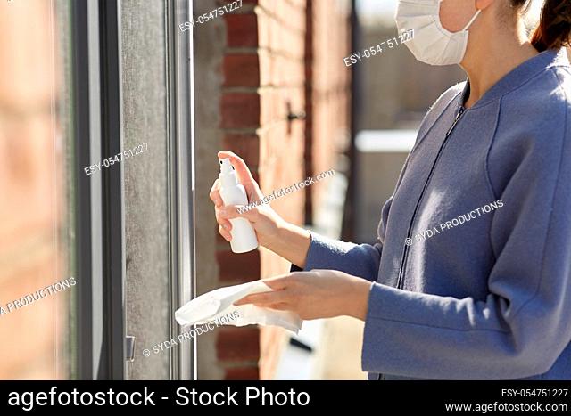 woman cleaning door handle with disinfectant spray
