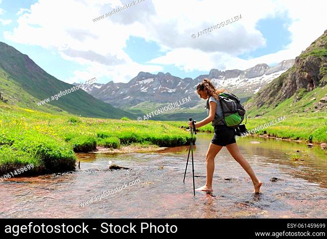 Side view portrait of a barefeet hiker crossing a river in the mountain