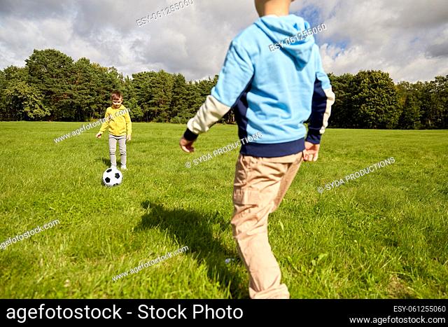 happy little boys with ball playing soccer at park