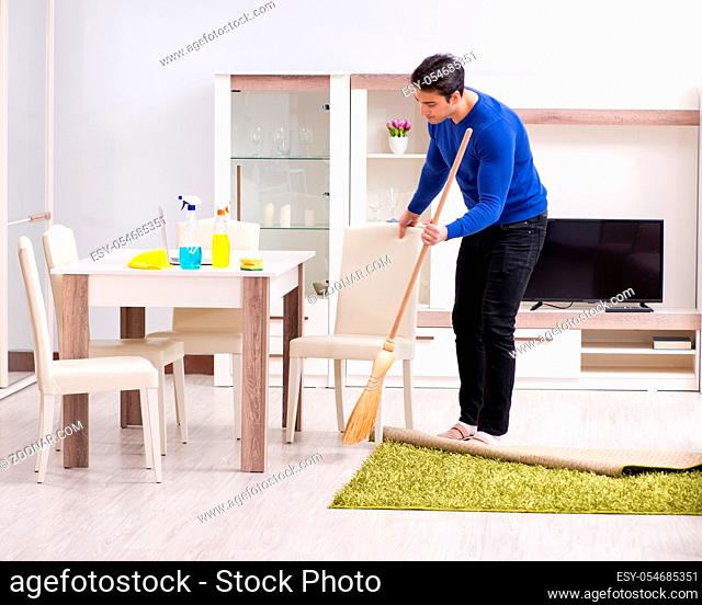 The young man cleaning floor with broom