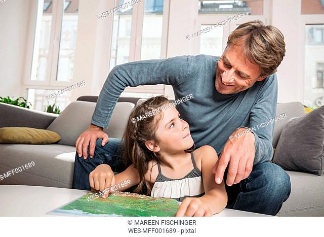 Father and little daughter with map in the living room