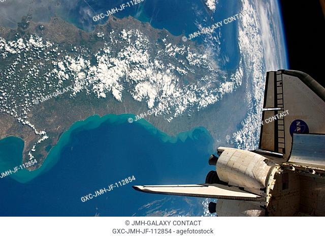 Backdropped against a scene showing part of Italy, this image featuring an aft section of the space shuttle Endeavour in the foreground was photographed by an...