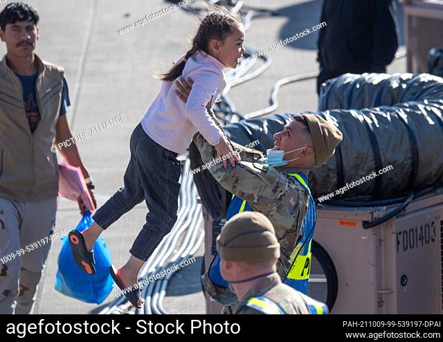 09 October 2021, Rhineland-Palatinate, Ramstein: A US military policeman twirls a little girl from Afghanistan through the air at the US airbase in Ramstein for...