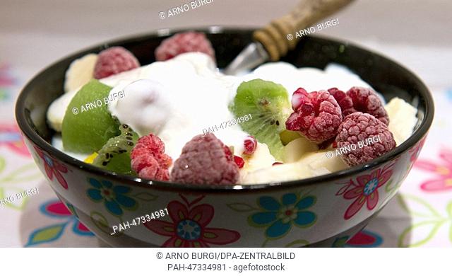 A bowl of Muesli, kiwis,  rasperberries, bananas, cape gooseberries, mango, yoghurt and milk sits on a table during breakfast in Dresden, Germany, 19 March 2014