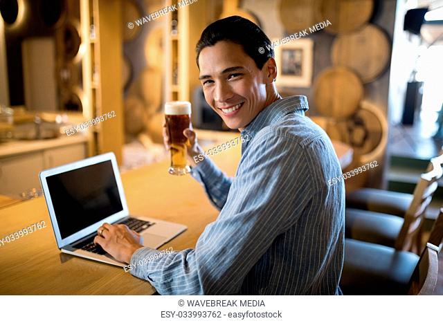 Man using laptop while having beer