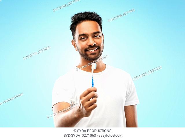indian man with toothbrush over blue background