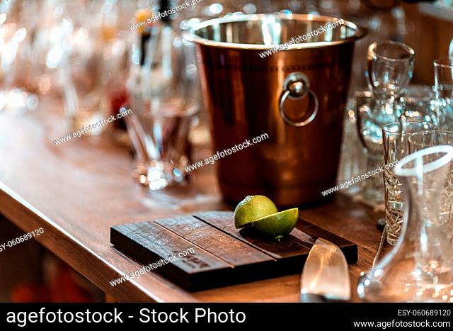 Halved fresh lime on a cutting board with a silver bucket on the background