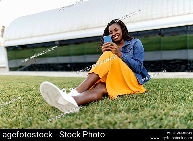 Young woman using smart phone sitting on grass