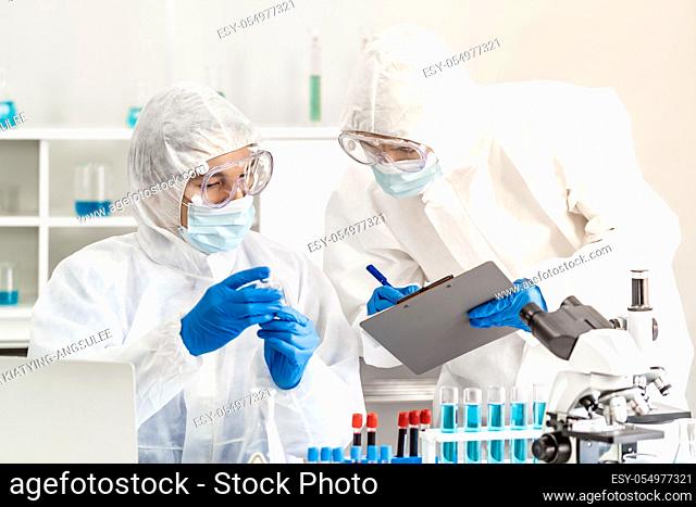 Scientist examine vaccine testing of coronavirus covid-19 pandemic in science lab. Scientist wear PPE personal protective suits and medical goggles