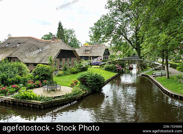 GIETHOORN, NETHERLANDS - JULY 18, 2015: Unknown tourists on boating trip in a canal in Giethoorn on july 18 2015. The beautiful houses and gardening city is...