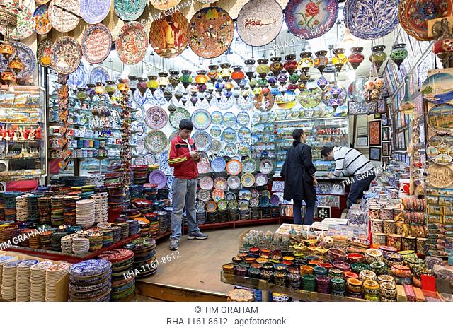 Man using smartphone in ceramics and souvenirs stall in The Grand Bazaar (Great Bazaar) (Kapali Carsi), Beyazi, Istanbul, Turkey, Europe